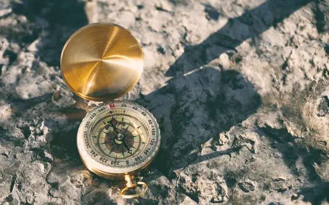 Brass compass lying open on a sunlit rocky surface