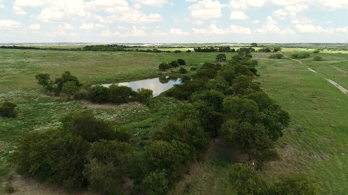 Aerial view of green North Texas prairie with trees and a pond