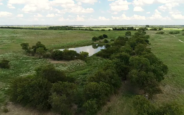 Aerial view of green North Texas prairie with trees and a pond
