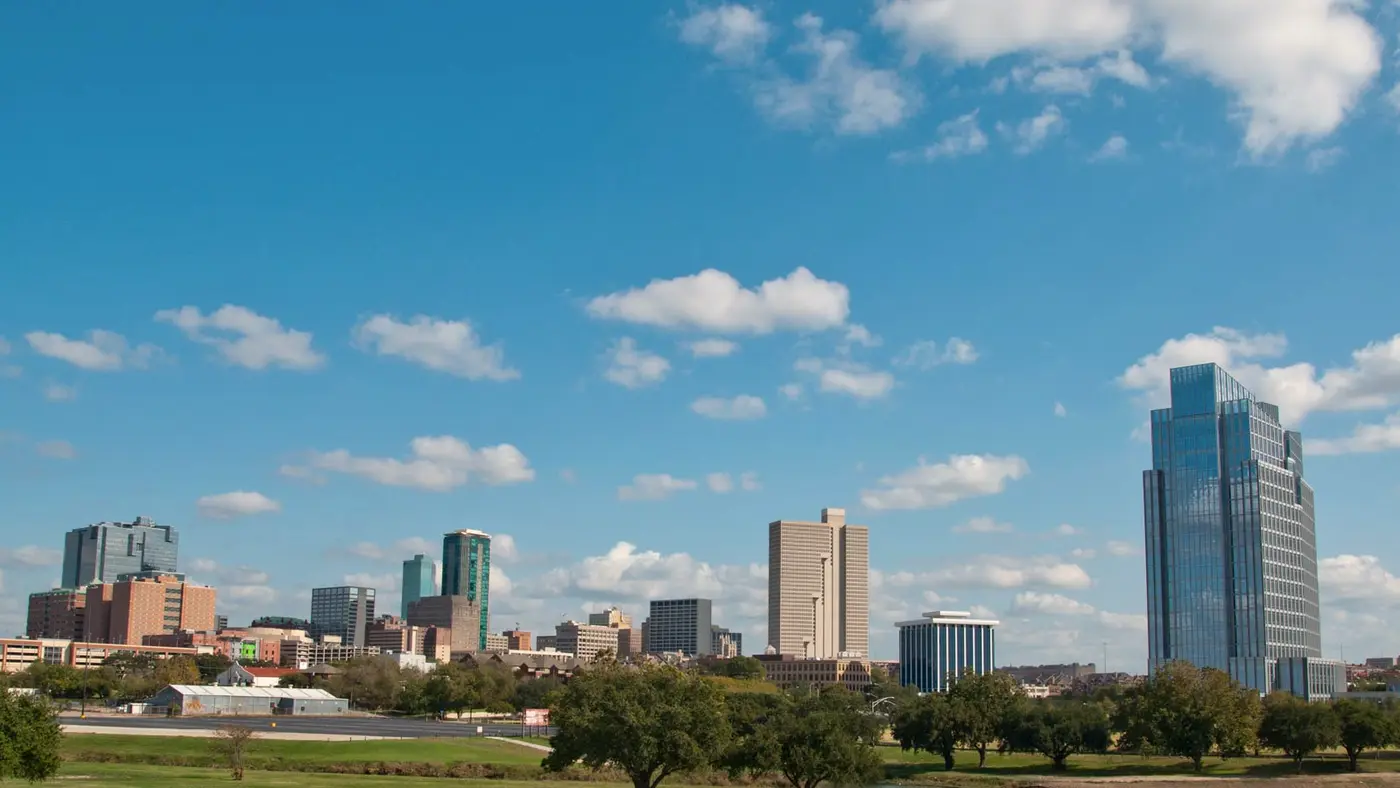 Fort Worth skyline beneath a blue sky with white clouds