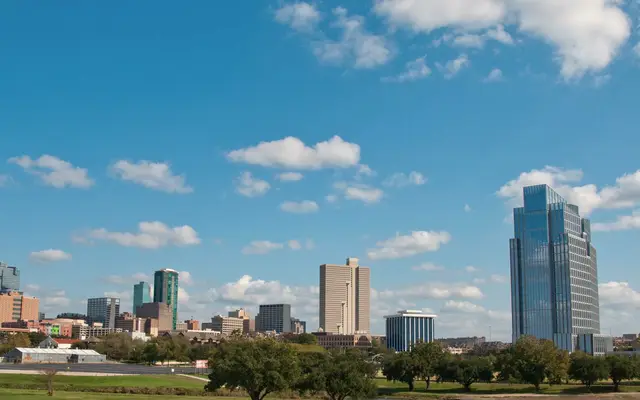 Fort Worth skyline beneath a blue sky with white clouds