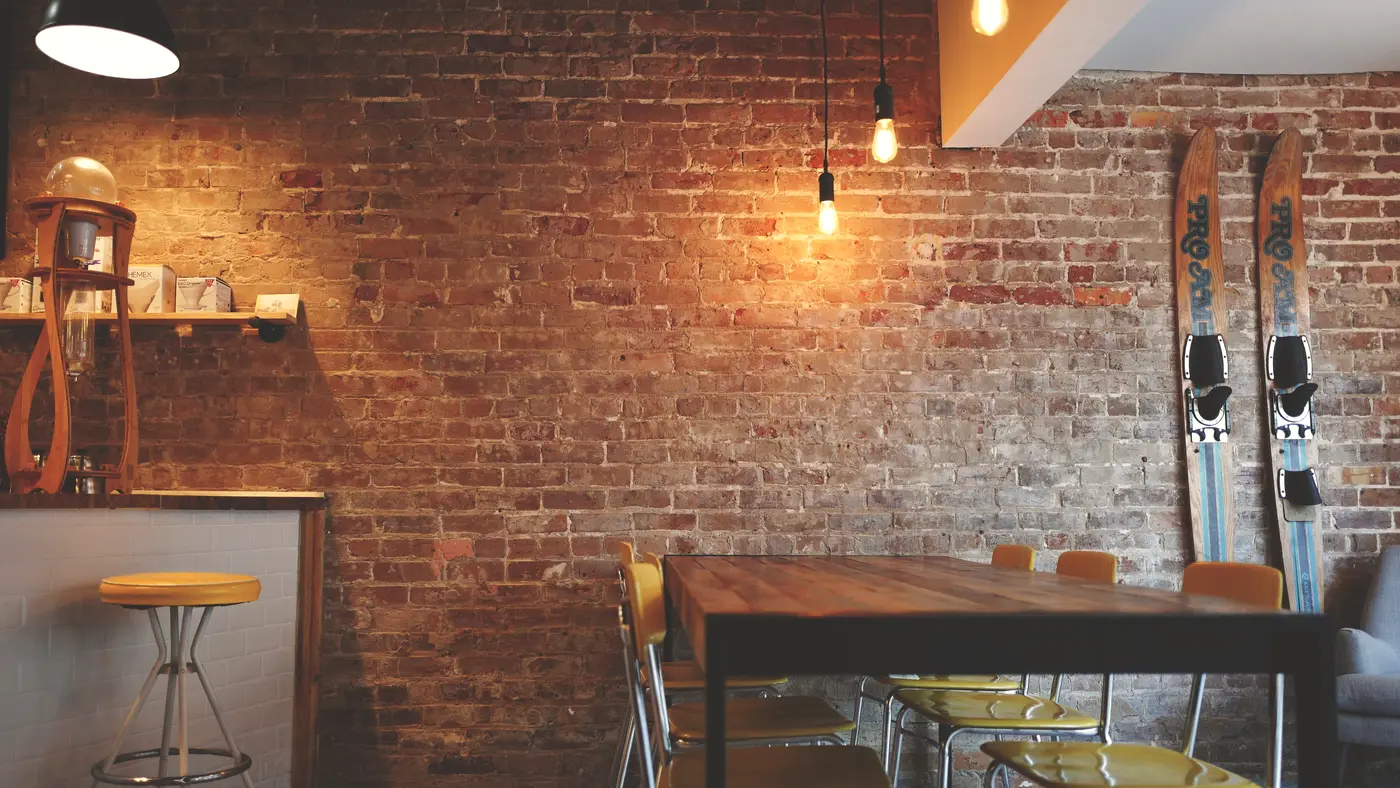 Empty cafe interior with brick wall, wooden tables and bar stools
