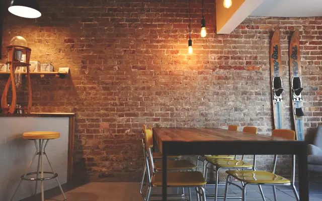 Empty cafe interior with brick wall, wooden tables and bar stools