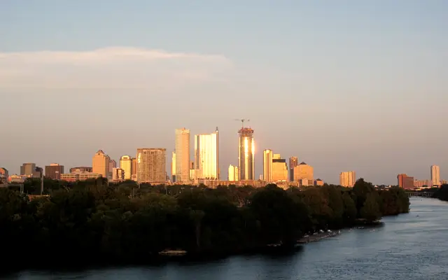 Austin skyline glowing in golden light beyond the river and trees